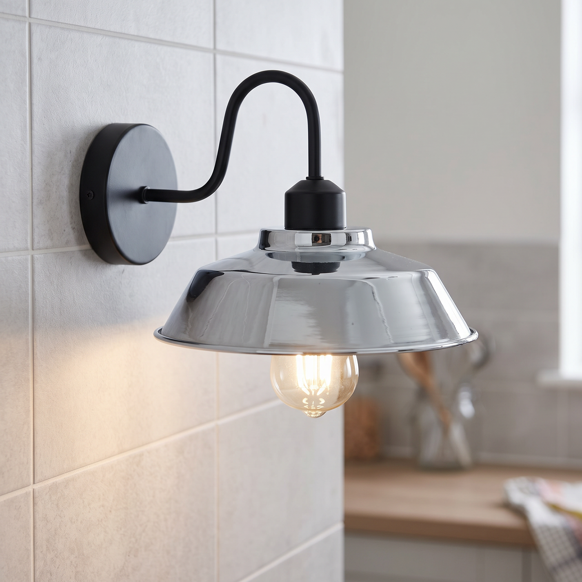 Gooseneck barn wall light with chrome shade on a kitchen wall