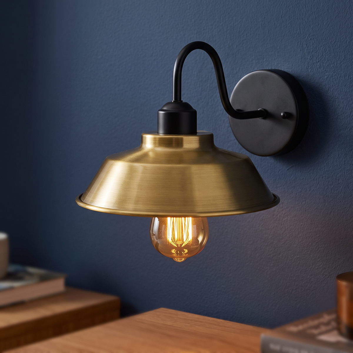 Gooseneck barn wall light with yellow brass shade on a navy wall