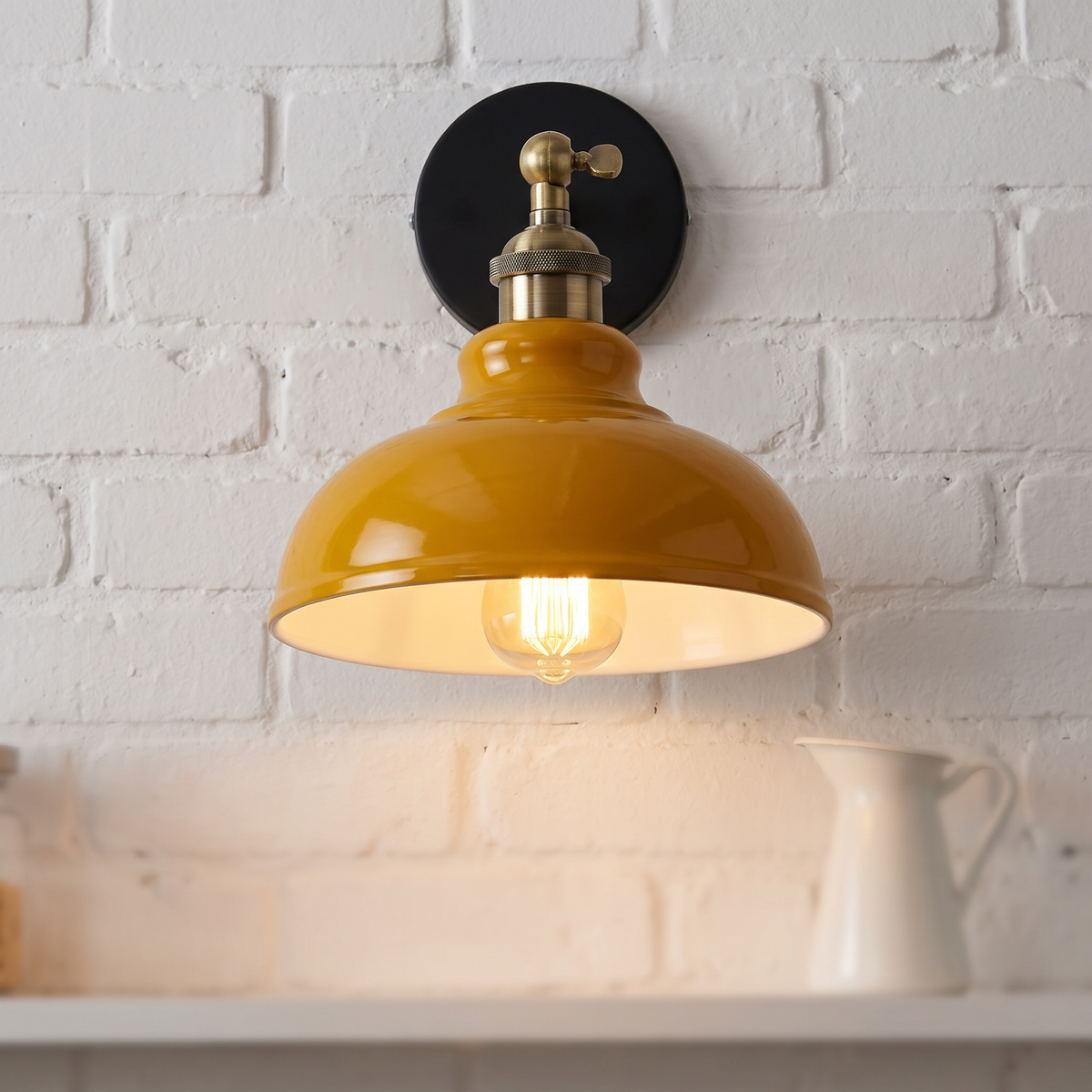 Vintage industrial dome wall light in mustard yellow on a white brick kitchen wall