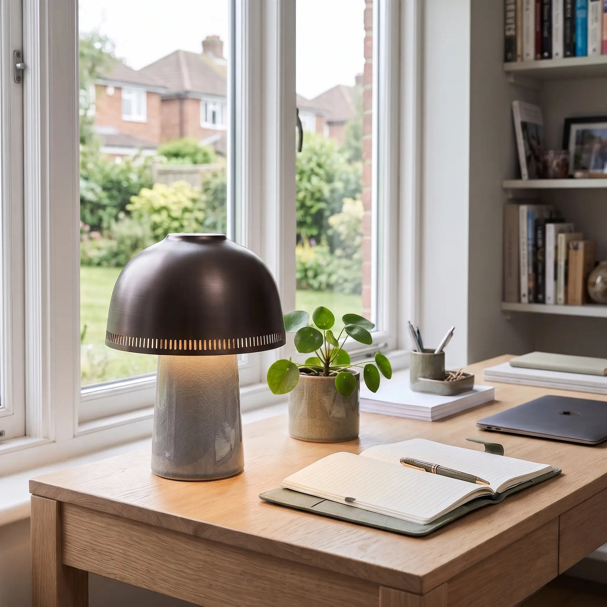 Grey ceramic table lamp with brown dome shade on a desk
