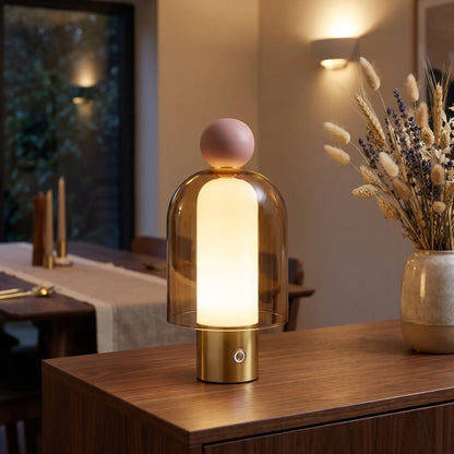 Cognac glass cordless lamp with pink top on a sideboard