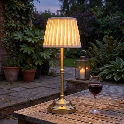 Pleated cordless table lamp on a garden table at dusk