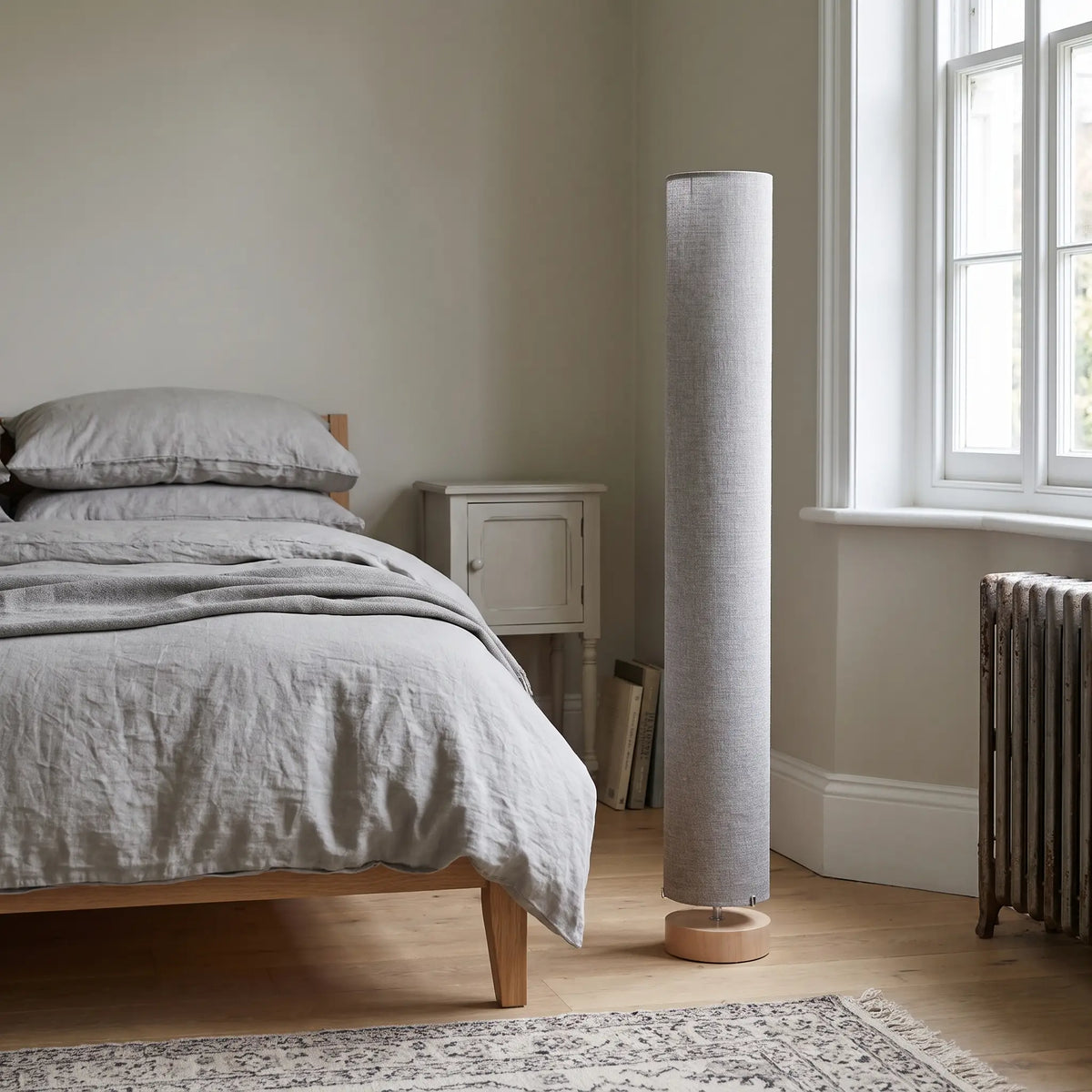 Grey linen column floor lamp in a bedroom in daylight