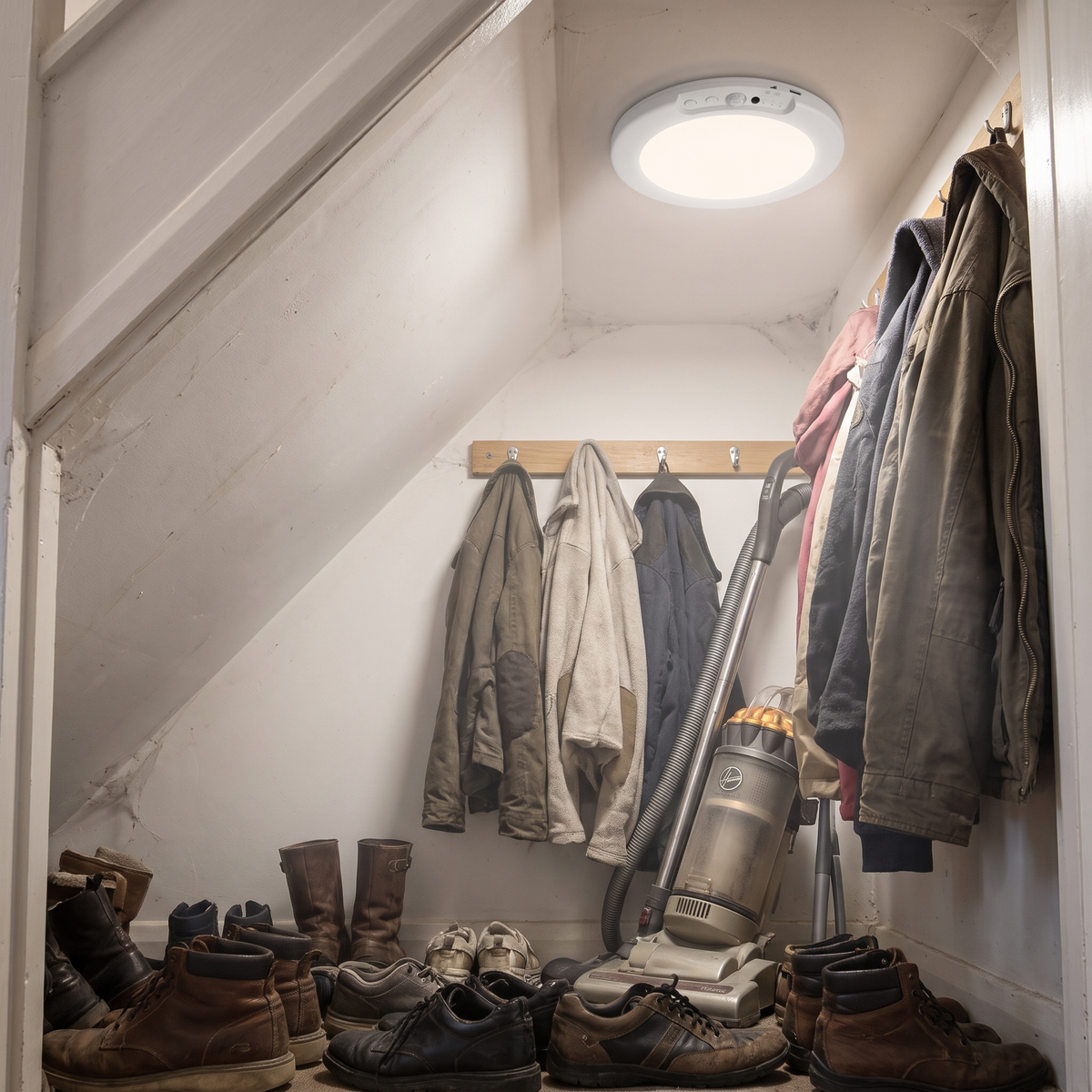 Round rechargeable ceiling light in an under-stairs cupboard